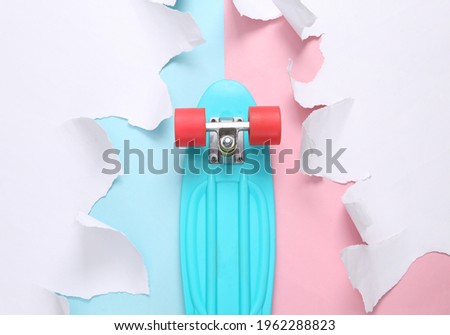 Penny board with white torn paper sheets on pink blue background. Minimalistic creative background.
