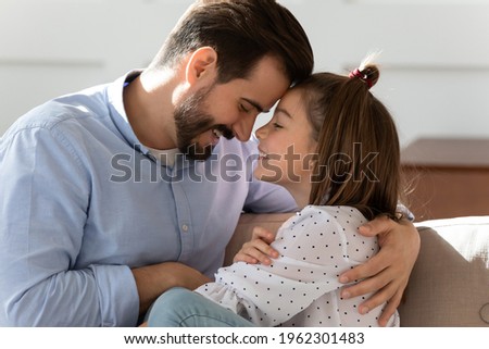 Caring young Caucasian father and little teenage daughter hug cuddle enjoy close intimate family moment at home together. Loving happy dad parent and teen girl child embrace share secrets. Royalty-Free Stock Photo #1962301483