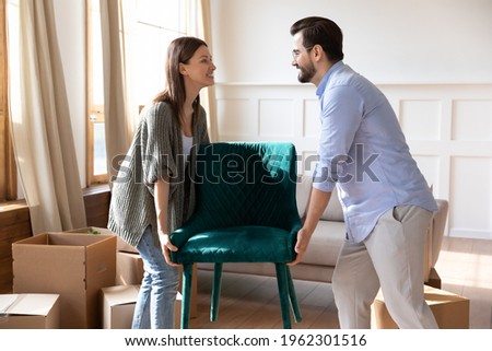 Happy young Caucasian man and woman tenants settle in new modern house or apartment. Smiling millennial couple renters unbox unpack in own home moving relocating together. Rental concept. Royalty-Free Stock Photo #1962301516