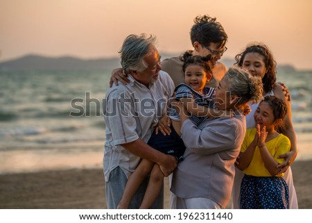 Happy big Asian family on beach holiday vacation. Multi-generation family holding hands and walking together on tropical beach at summer sunset. Family enjoy and having fun outdoor activity lifestyle. Royalty-Free Stock Photo #1962311440