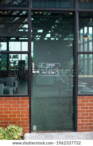 Outside glass door of modern cafe restaurant with Open sign, No smoking, No pet, no food and drink, Dayli Mon-fri. Loft coffee shop exterior with red brick wall background and eco green glass