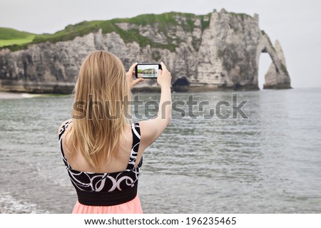 Girl takes picture of beautiful rock in Etretat, Normandy, France