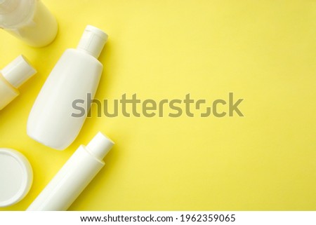 Skin and body care cosmetic. White blank plastic bottles on yellow background. Copy space for text