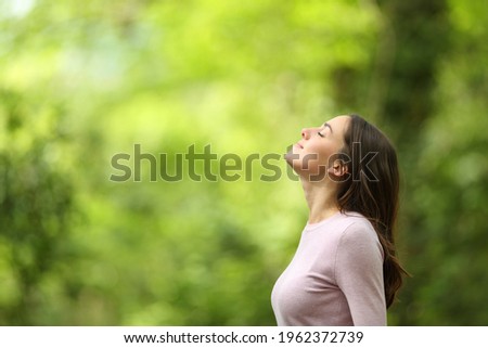 Profile of a relaxed woman breathing fresh air in a green forest Royalty-Free Stock Photo #1962372739