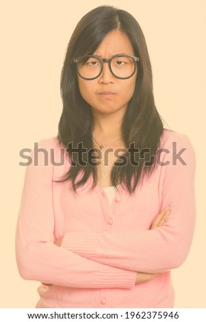 Portrait of stressed young Asian nerd woman looking angry with arms crossed