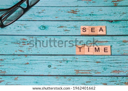 Top view sea time lettering of alphabet wooden blocks on blue wooden background