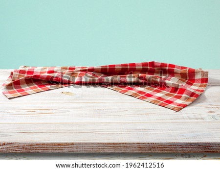 Blank red checkered tablecloth on a wooden table in perspective. Selective focus.
