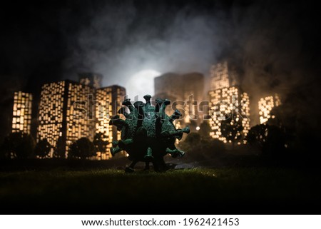Cartoon style city buildings. Realistic city building miniatures with lights. Big Corona virus miniature in the city at night. Stay home stay safe or coronavirus pandemic concept. Selective focus.