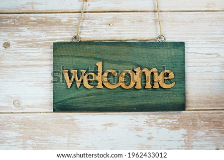 Welcome sign hanging on wooden background