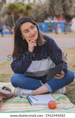 Young college student studying in the park, taking notes and learning all about her subjects.