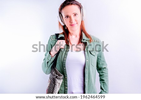 Self-confident beautiful young woman on white background wearing casual clothes and music headphones