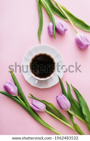 Cup of coffee and purple tulips on pink background. Flat lay, top view. Flower composition. Spring time morning concept