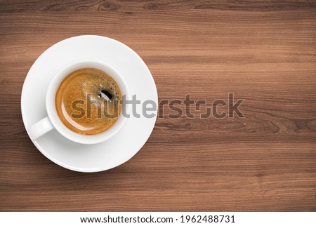 Top view of Hot Coffee in white cup and plate on beautiful wooden table.