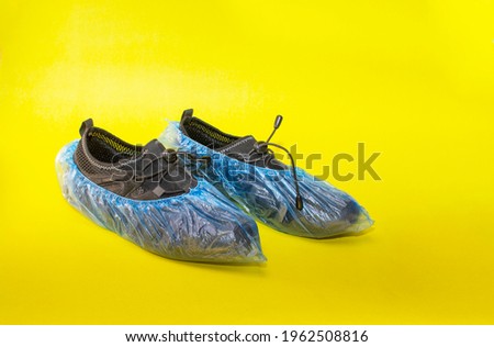 black sneakers in shoe covers on a yellow background. 