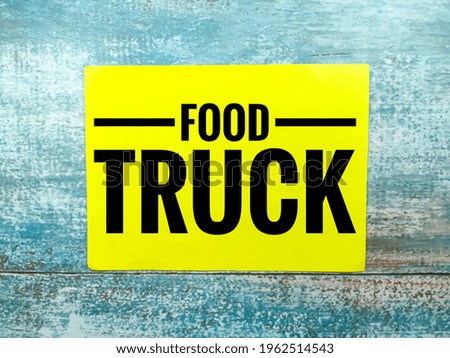 Text FOOD TRUCK on colorful paper with blue wooden background.