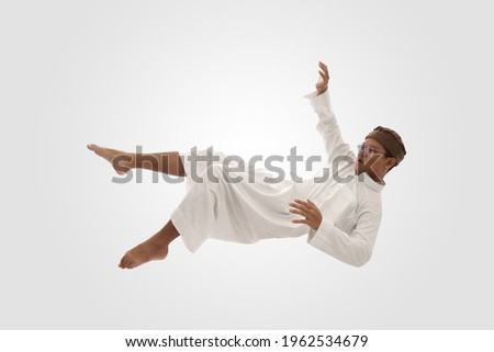 young man jumping in air or falling down. Mid-air shot of handsome young man falling against white background. levitation concept Royalty-Free Stock Photo #1962534679