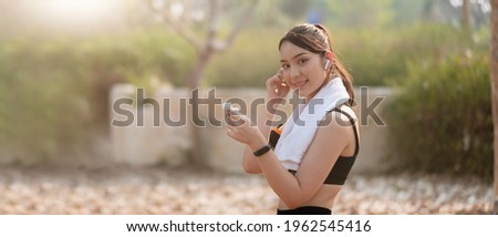 Photo of a beautiful asian young fitness woman running outdoors listening music with earphones