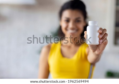 Happy young African American woman holding bottle of dietary supplements or vitamins in her hands. Healthy lifestyle concept Royalty-Free Stock Photo #1962569494