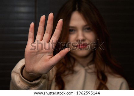Young woman shows Stop signal. Palm and gestures. Inaccessibility and negativity.