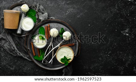 Vanilla sweet ice cream with mint. Ice cream spoon. On a black stone background, top view.