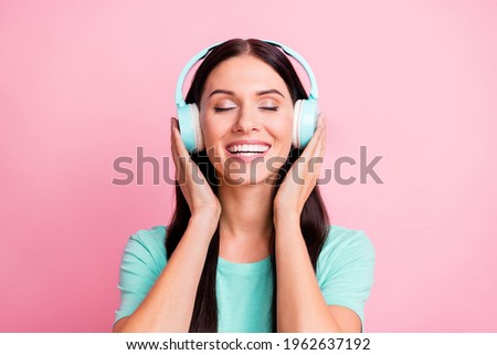 Portrait of young beautiful excited smiling positive girl in headphones listening music isolated on pink color background