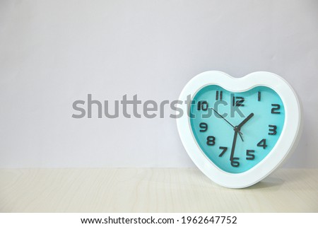 Heart-shaped alarm clock, white frame, blue clock face dial, copy space