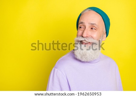 Photo of cute attractive age gentleman wear violet sweater headwear smiling looking empty space isolated yellow color background
