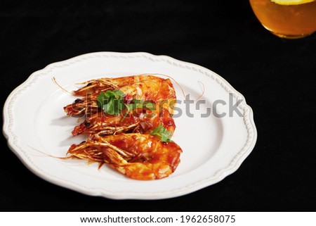 Fried shrimps with soy sauce in white plate, seafood, black background