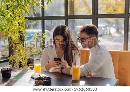Friends socializing, having fun, and laughing drinking coffee in coffeehouse while fooling around. Male and female friends Taking pictures together on a sunny day.