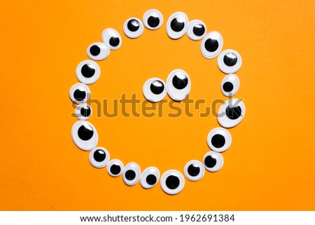 Smile laid out of toy eyes on a monochrome orange background
