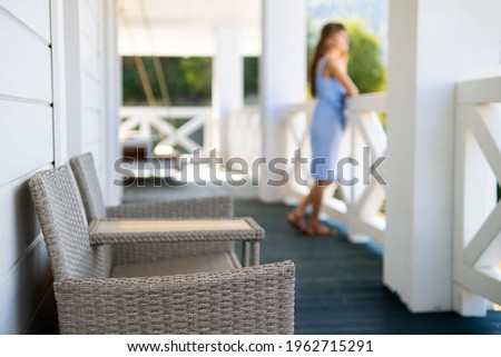 Blurred view of woman in blue dress standing on balcony and looking on nature. Concept of enjoying fresh air and nature.
