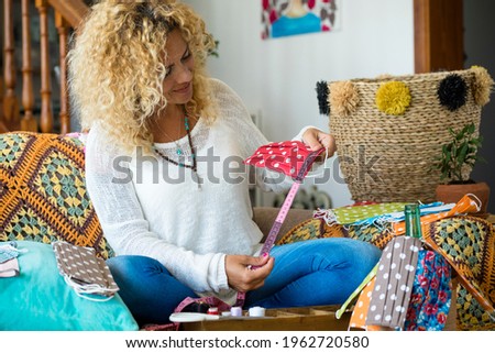 Female people leisure work indoor activity sit down on the sofa with colorful hand made creative medical protecion mask for coronavirus covid-19