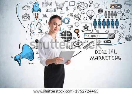 Businesswoman holding tablet device to discover future perspective in development of digital marketing. Social media icons sketch on concrete wall background.