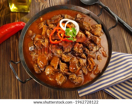 Fine Meat - Beef Goulash in a Pan with Red Pepper on wooden Background. Royalty-Free Stock Photo #1962728122