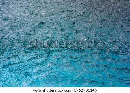 Rain fall on the pool in rains season. Close up of blue water waves, low angle view. Selective focus. Background texture. High quality photo
