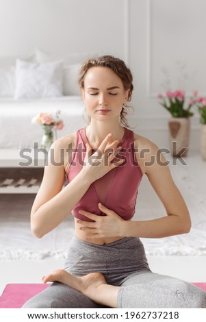 The girl does yoga. Curly woman at home practices asanas. Hands on chest, mudra. Royalty-Free Stock Photo #1962737218