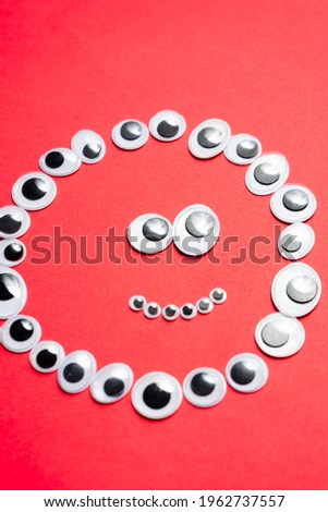 Smile laid out of toy eyes on a monochrome red background