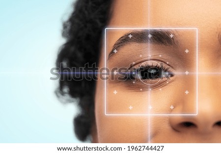 vision correction, laser eye surgery and health concept - close up of young african american woman face over blue background Royalty-Free Stock Photo #1962744427