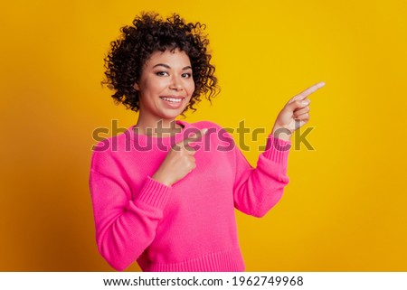 Portrait of cheerful pretty girl indicate finger copyspace isolated over yellow color background