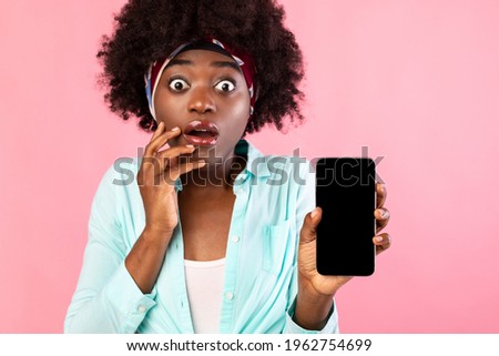 Shocked Black Woman Showing Smartphone With Blank Screen To Camera Advertising New Amazing Application For Cellphone Posing Over Pink Background. Shocking Mobile News Concept. Studio Shot, Mockup