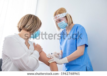 Doctor in personal protective suit inject vaccine shot to stimulating immunity of woman patient at risk of coronavirus infection. Coronavirus,covid-19 and vaccination concept