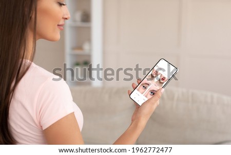 Beauty App. Over Shoulder View Of Smiling Woman Using Modern Application With AR Makeup Simulation, Trying Different Lipstick And Eyeshadow Color Online On Phone, Looking At Before And After Result