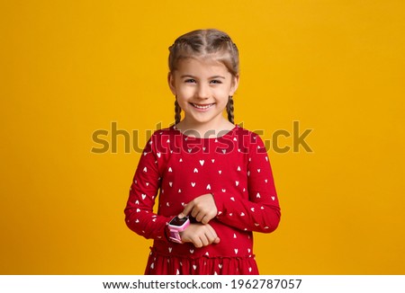 Little girl with smart watch on yellow background