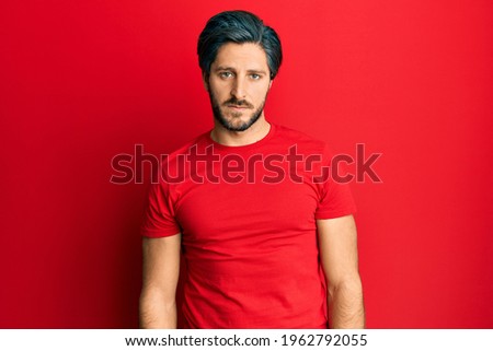 Young hispanic man wearing casual red t shirt looking sleepy and tired, exhausted for fatigue and hangover, lazy eyes in the morning. 