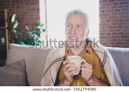 Photo of positive person sit on couch hands hold beverage look curious far thinking imagine free time indoors