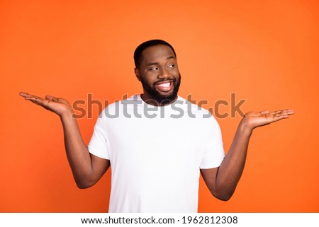 Photo of happy brunette afro american dream young man look hands empty space isolated on orange color background