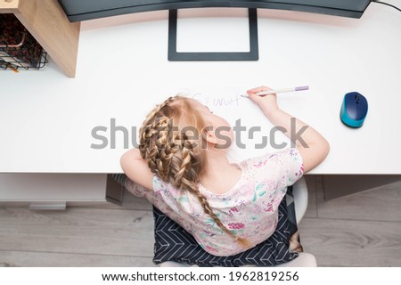 Top view of preschool girl with a wrong posture sitting at the desk, learning to write. Home schooling, education concept Royalty-Free Stock Photo #1962819256