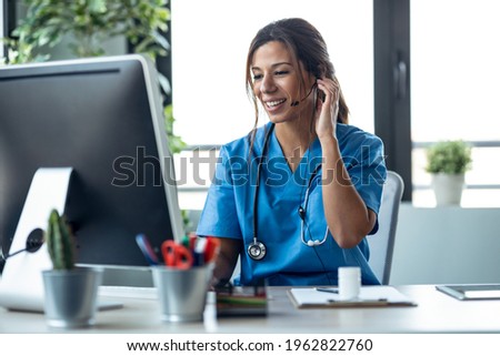 Shot of female doctor talking with earphone while explaining medical treatment to patient through a video call with computer in the consultation. Royalty-Free Stock Photo #1962822760