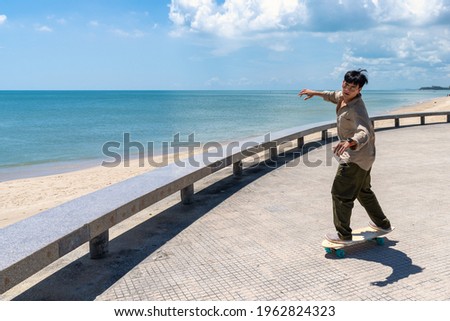 Young asian man riding surfskate board. Trendy outdoor sport in Thailand, Asia.