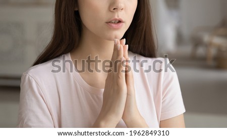 Faithful young woman keeping hands together in pray to god. Cropped shot of religious teen girl, Christian church prayer asking for help or luck. Hope, worship, religion, belief concept. Closeup
